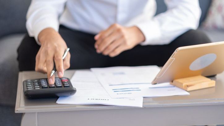 A company employee reviews his employee stock options on a tablet while doing some rough calculations.